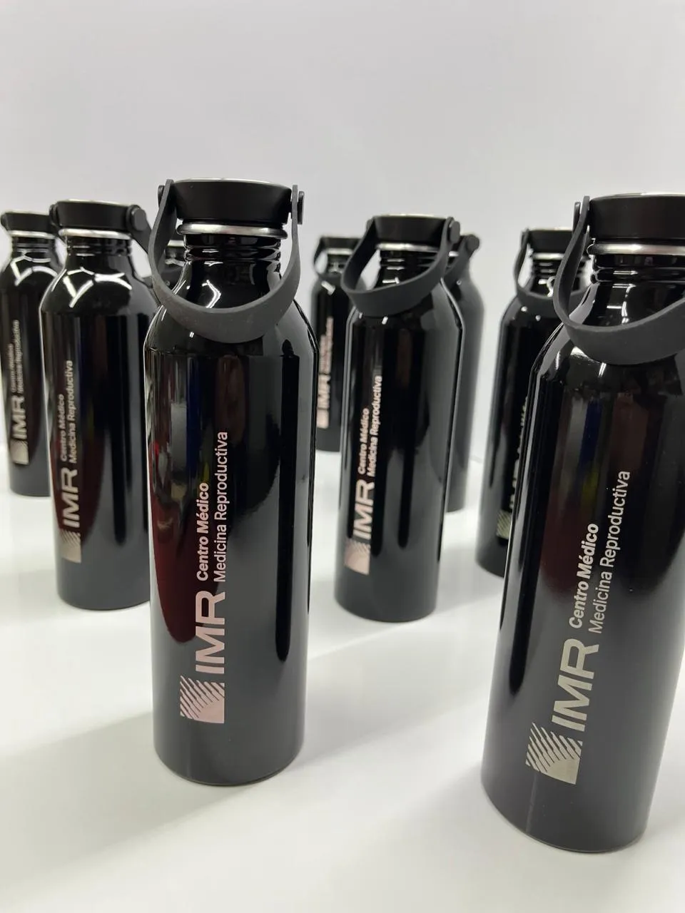 Botellas negras grabadas con el logo del Centro Médico IMR