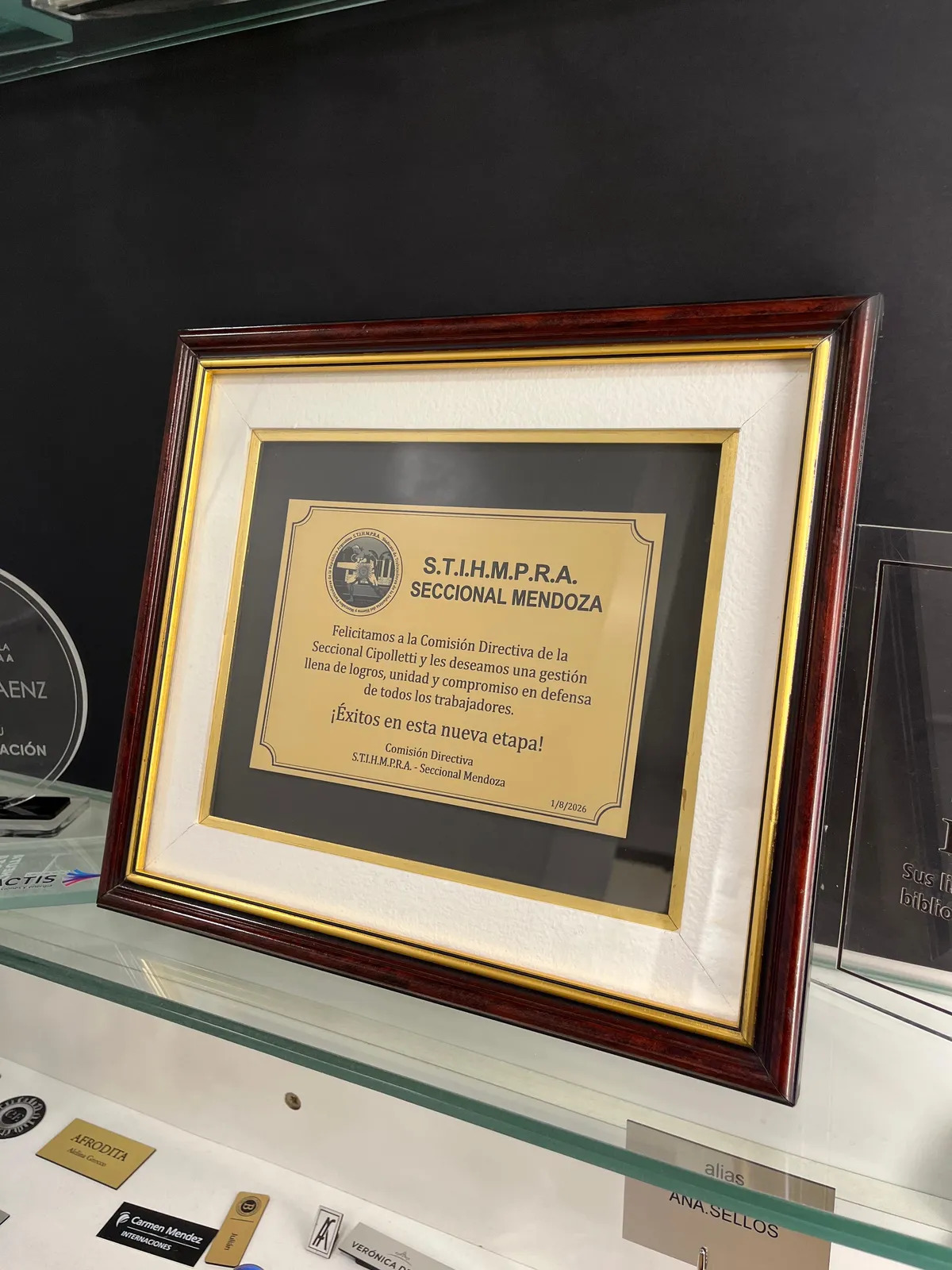 Placa dorada de reconocimiento grabada, enmarcada en madera